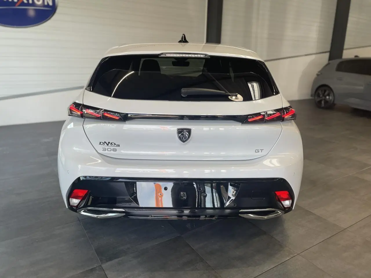 Vue arrière d'une Peugeot 308 GT blanche avec feux arrière à signature lumineuse et diffuseur noir brillant.