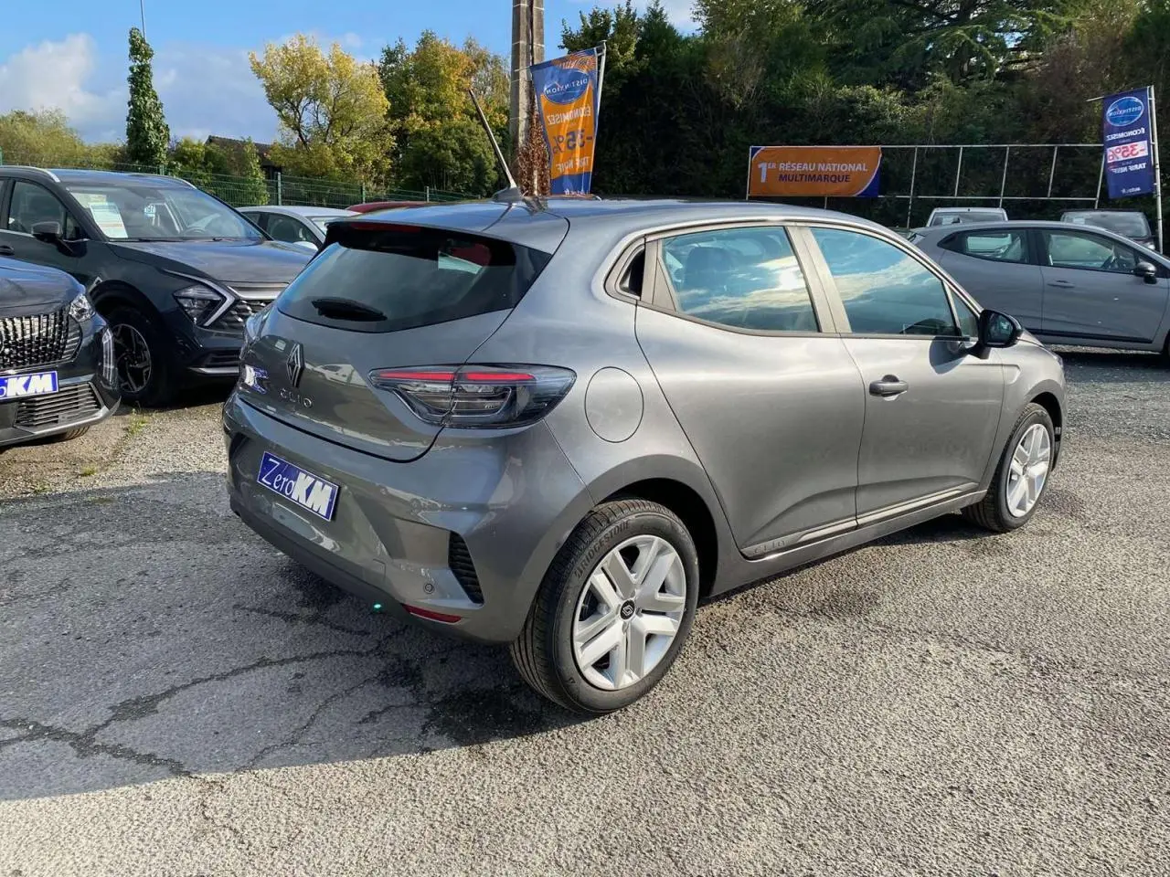 Renault Clio 2025 gris schiste vue 3/4 arrière droit sur parking avec antenne et jantes aluminium.