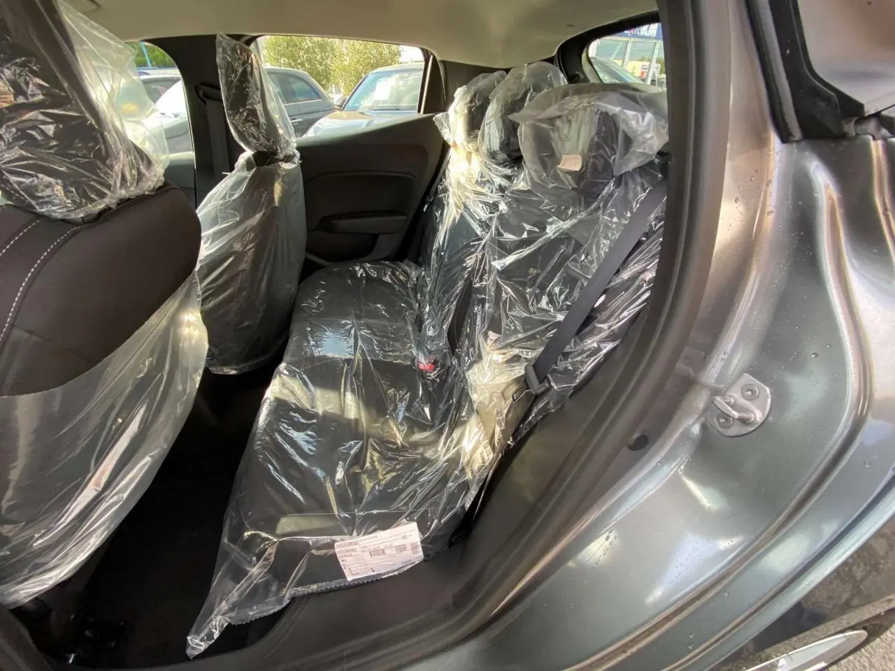 Vue intérieure arrière côté droit de la Renault Clio 1.5 Blue dCi 2025 gris schiste, sièges protégés par film plastique.