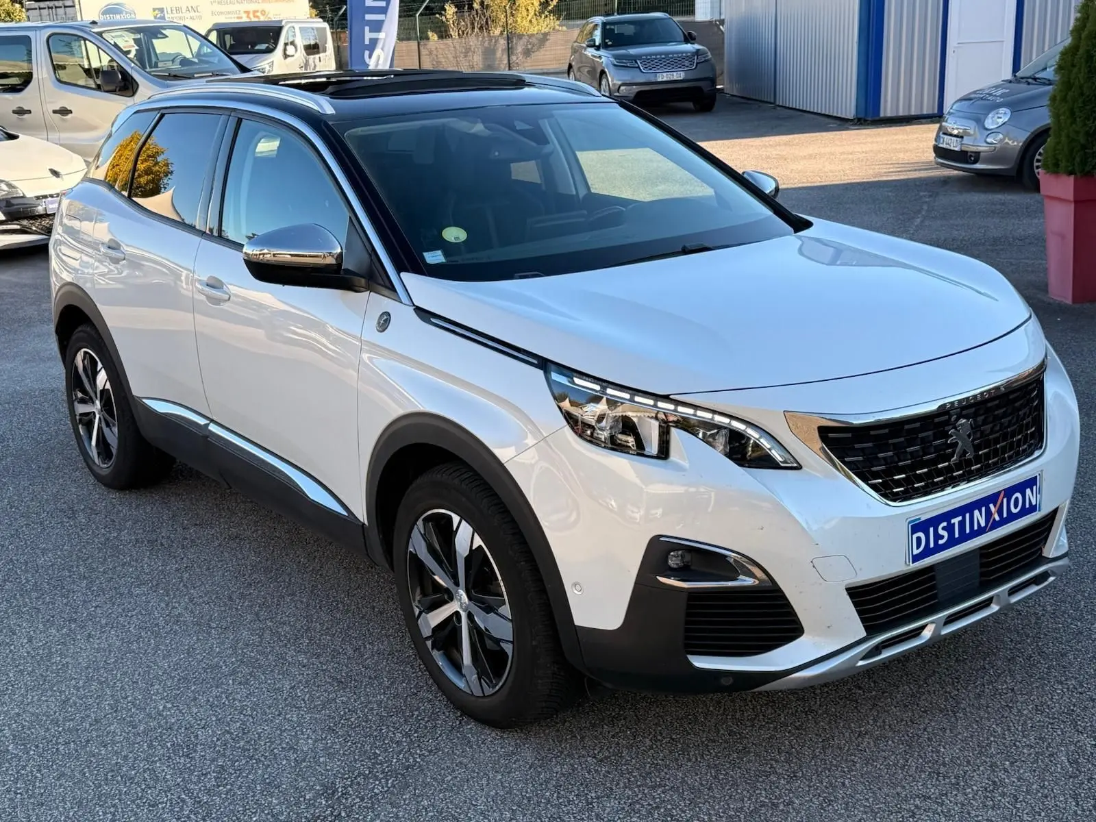 Vue 3/4 arrière droite d'un Peugeot 3008 blanc nacré avec feux arrière à trois griffes et jantes alliage bicolores.