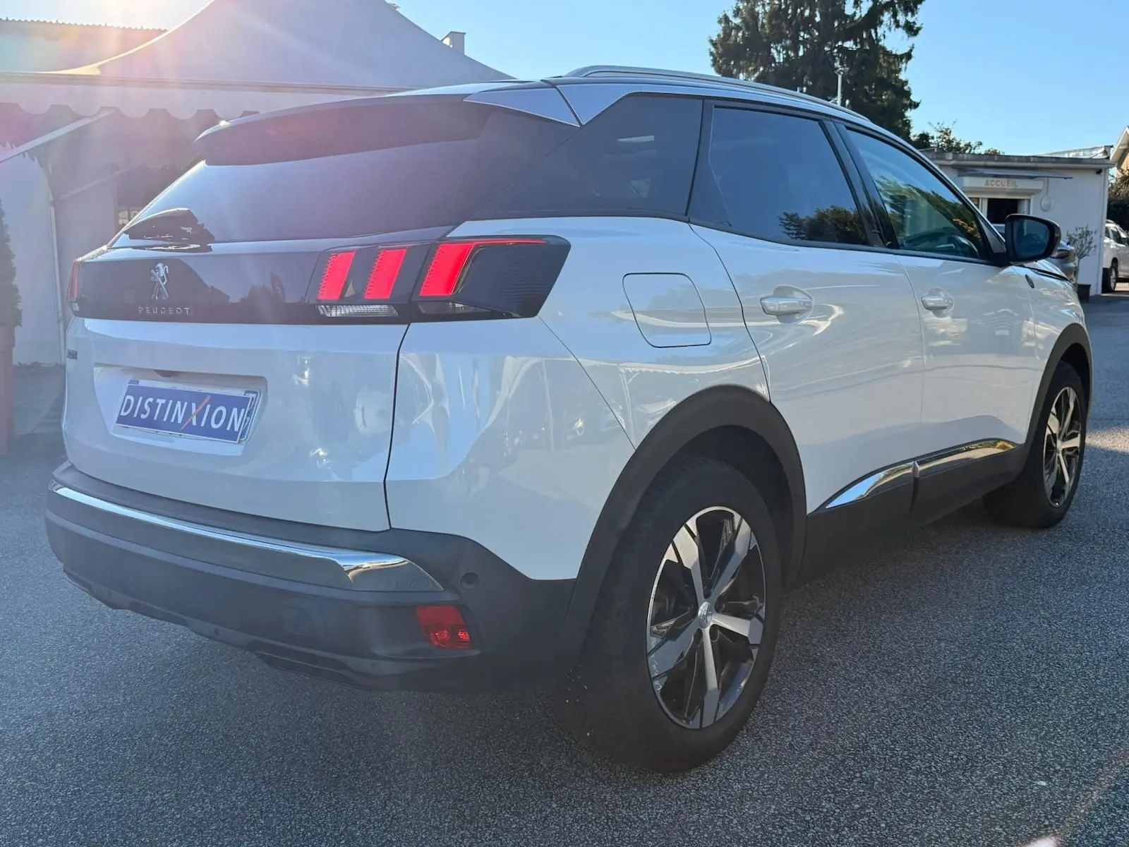 Peugeot 3008 blanc nacré vue 3/4 arrière côté gauche, avec toit noir et feux arrière à griffes rouges distinctifs.