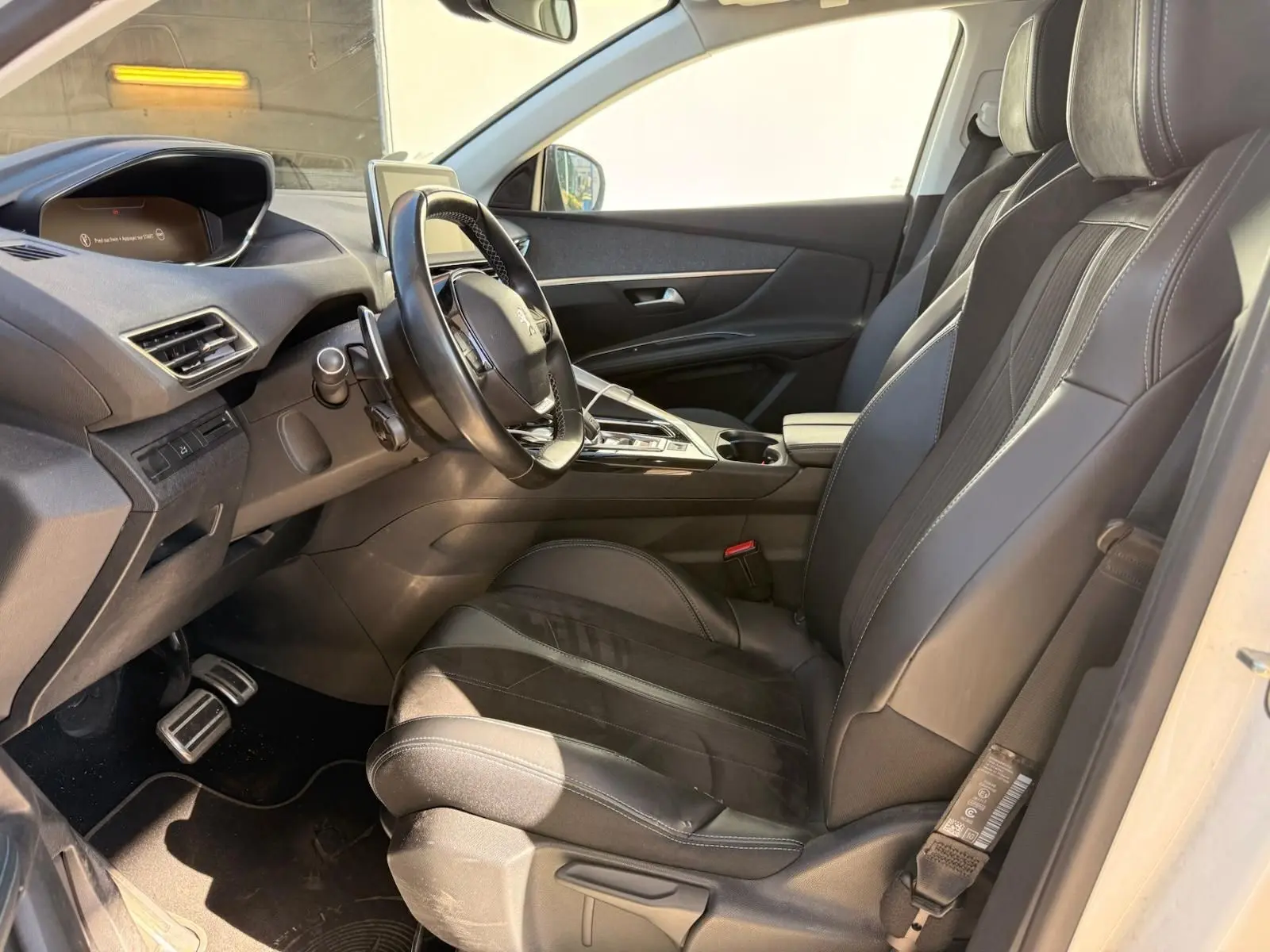 Intérieur côté conducteur du Peugeot 3008 blanc nacré 2019, sièges cuir noirs et tableau de bord moderne.