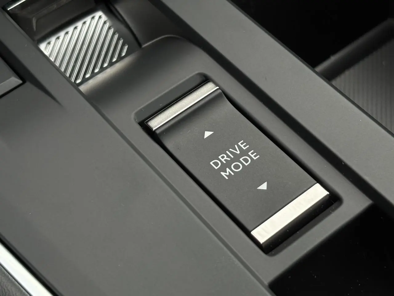 Gros plan sur le bouton Drive Mode noir et argenté de la console centrale du Citroën C5 Aircross Hybrid 2025.