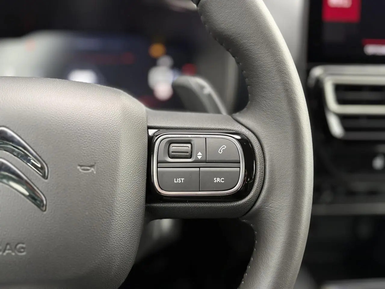 Gros plan sur les commandes gauche du volant noir du Citroën C5 Aircross Hybrid 2025 avec boutons multifonctions.