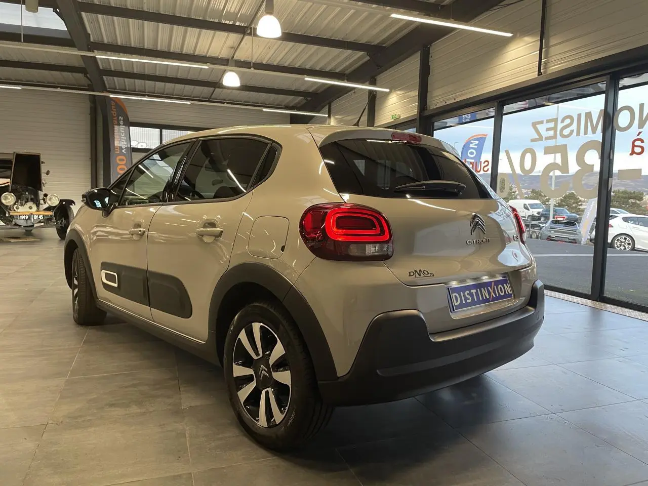 Vue 3/4 arrière droite d'une Citroën C3 beige clair avec Airbump noirs et jantes alliage diamantées en showroom.