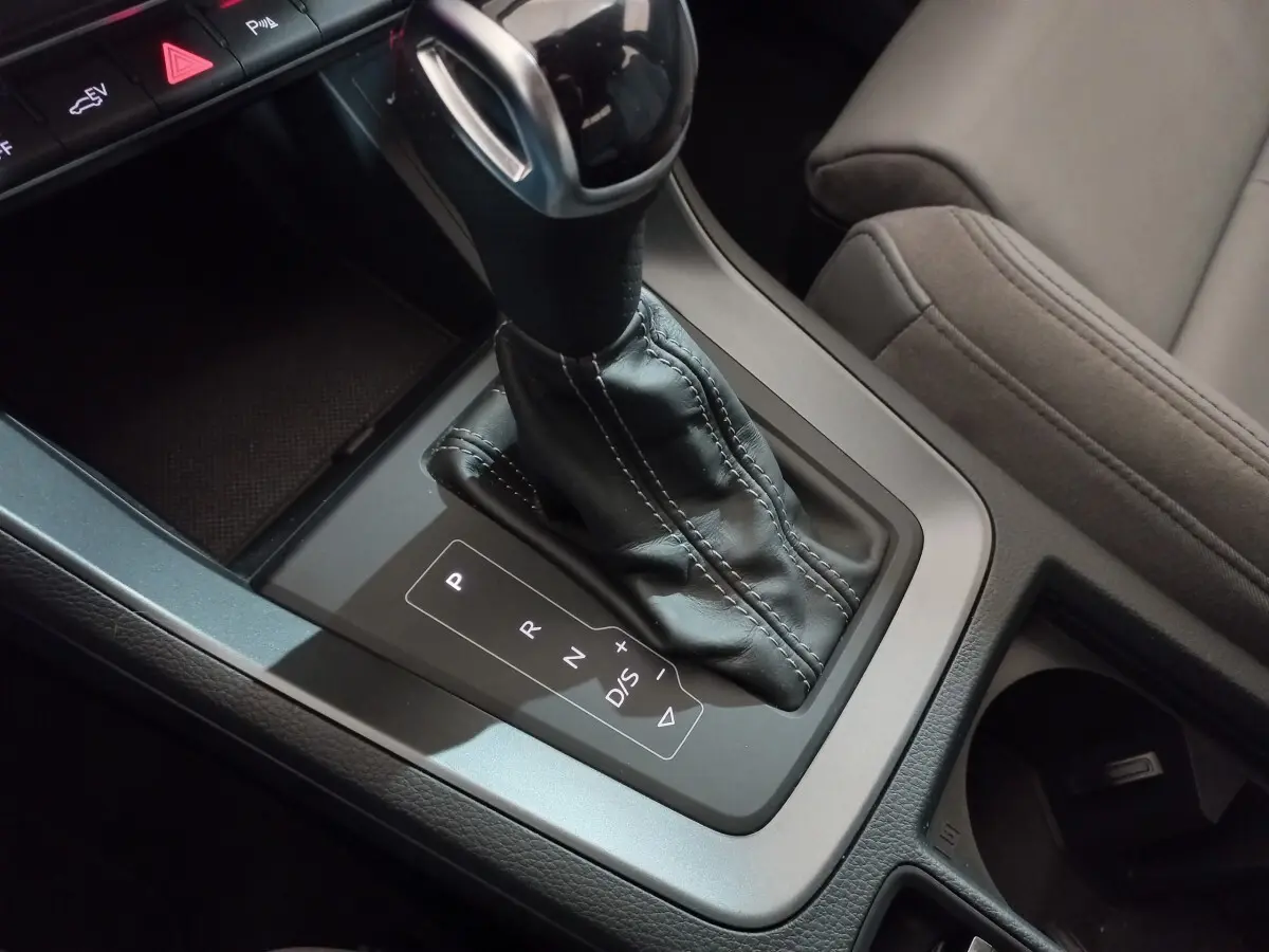 Gros plan sur la console centrale de l'Audi Q3 45 TFSI E 245 S tronic S line avec levier de vitesses cuir noir.