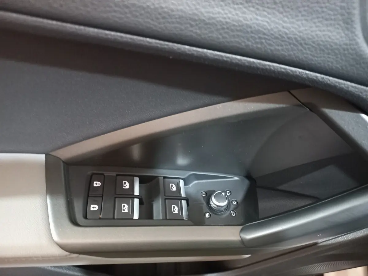 Gros plan sur les commandes de lève-vitres et réglage des rétroviseurs côté conducteur d'un Audi Q3 blanc 2021.