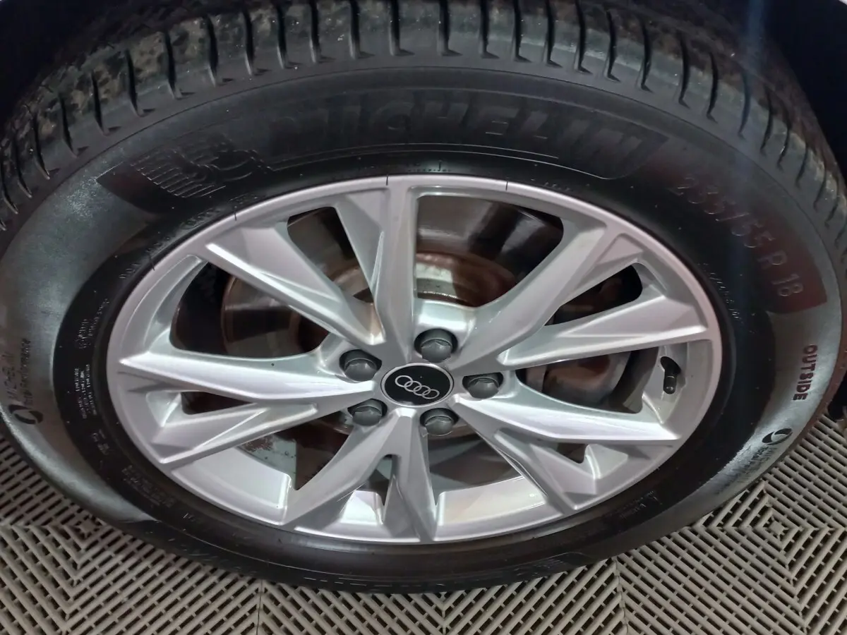 Gros plan sur la jante alliage argentée avec logo Audi au centre, montée sur pneu Michelin, vue de face.
