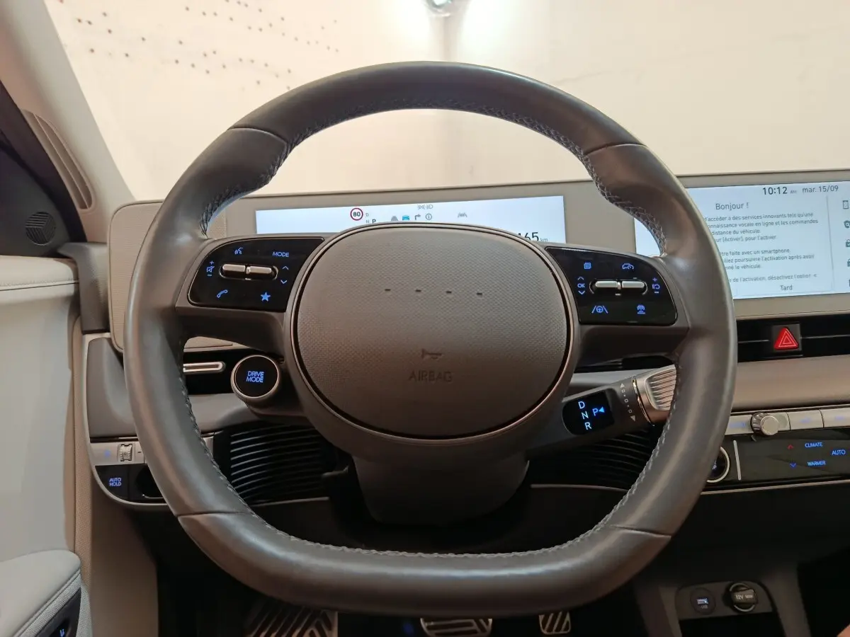 Vue frontale du volant cuir noir de la Hyundai IONIQ électrique 2023 avec tableau de bord digital et commandes intégrées.