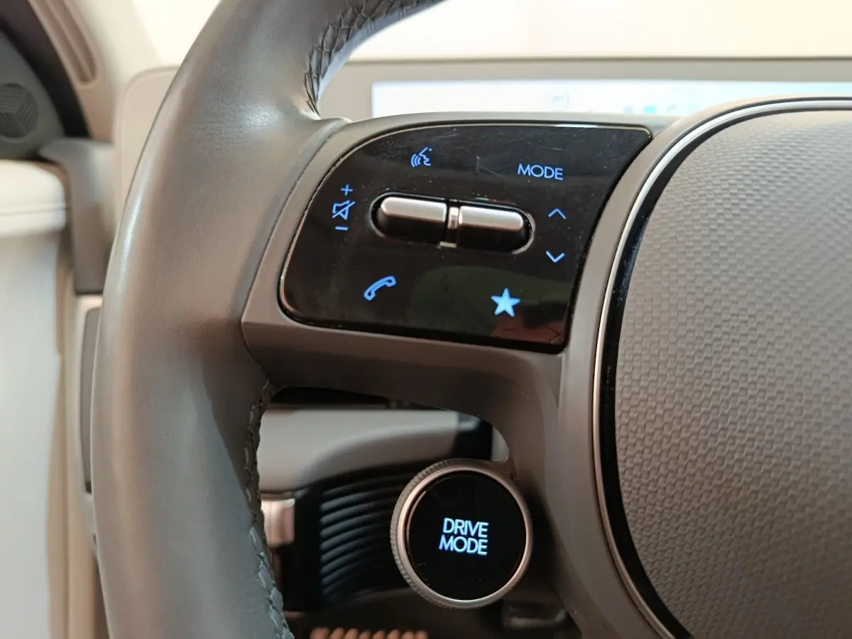 Gros plan sur le volant cuir beige de la Hyundai IONIQ 2023 avec commandes tactiles et bouton Drive Mode.