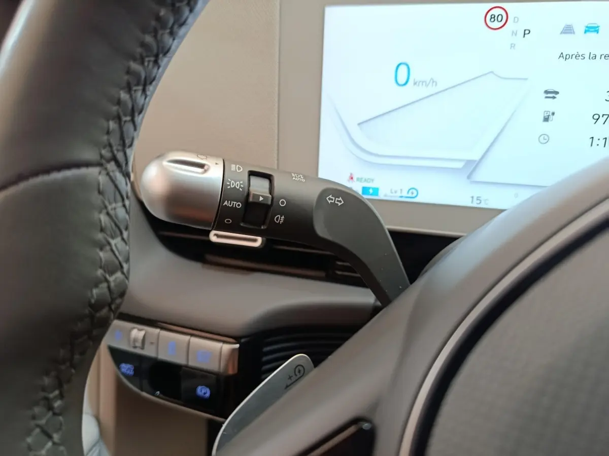 Gros plan sur la commande de clignotants et partie du volant cuir beige d'une Hyundai IONIQ BEV 77KWH AWD Executive 2023.