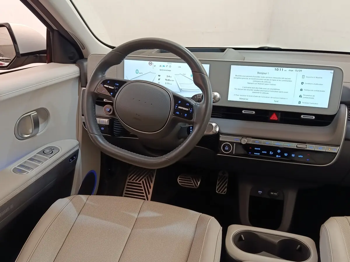 Vue intérieure côté conducteur du tableau de bord beige de la Hyundai IONIQ BEV 77KWH AWD Executive 2023 avec écran tactile large.