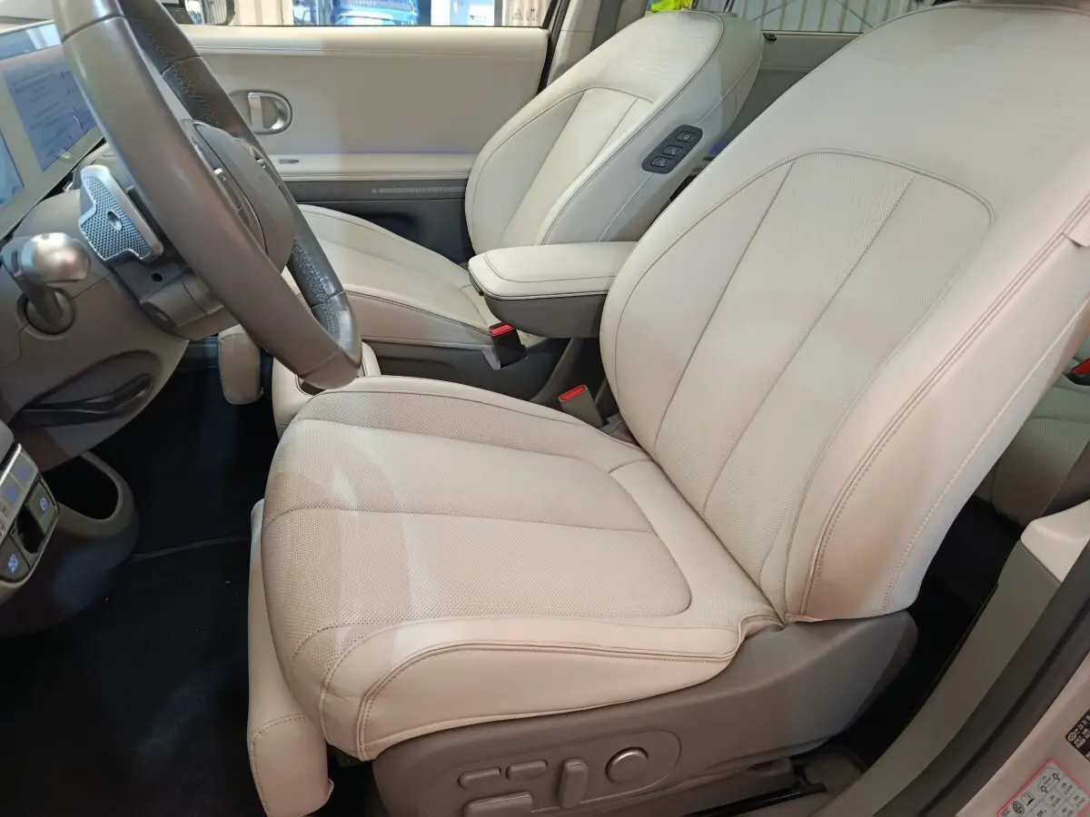 Vue intérieure côté conducteur du siège avant beige clair en cuir du Hyundai IONIQ BEV 77KWH AWD Executive 2023.