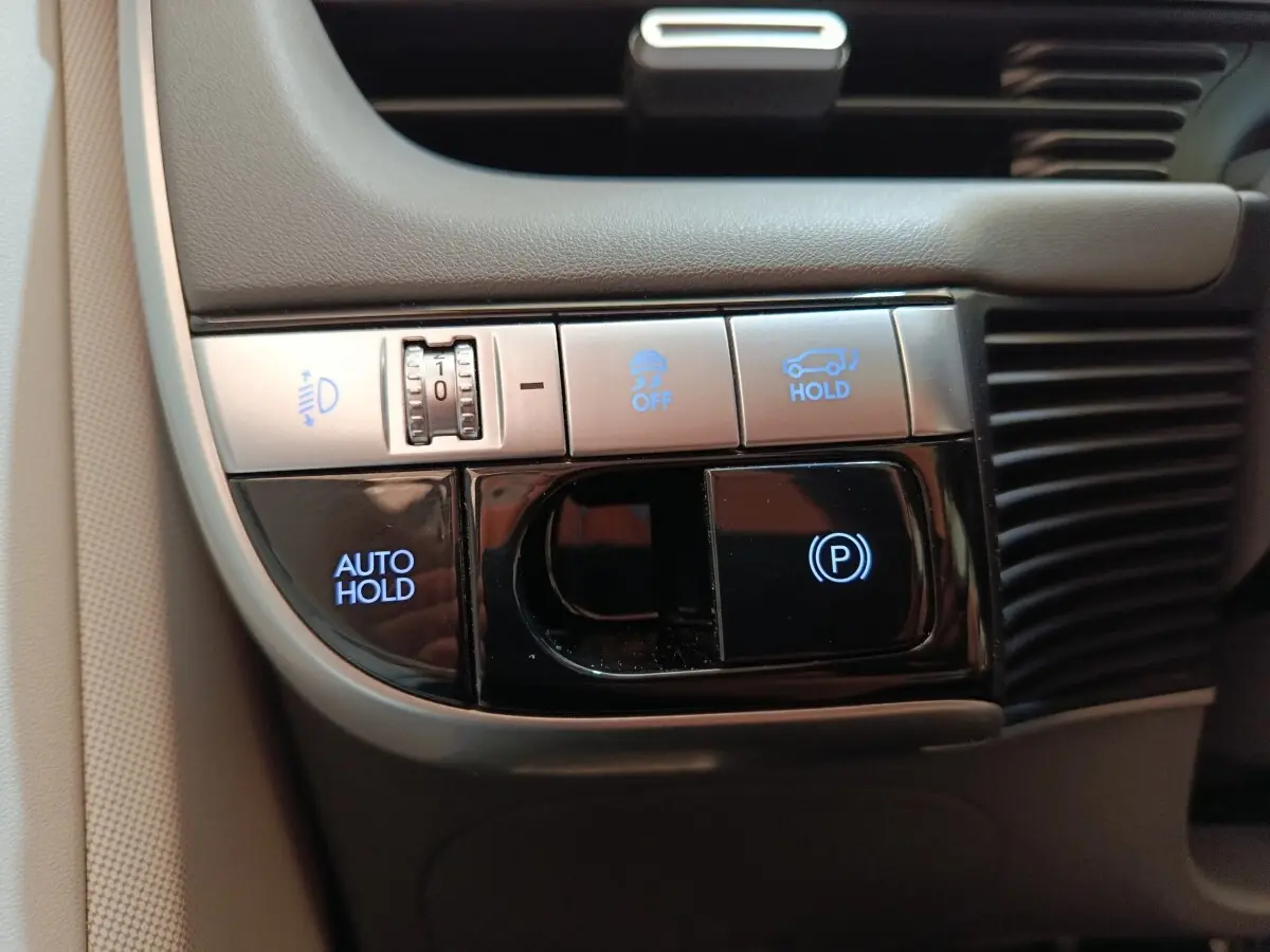 Gros plan sur les commandes de maintien automatique et frein de stationnement du Hyundai IONIQ beige 2023.