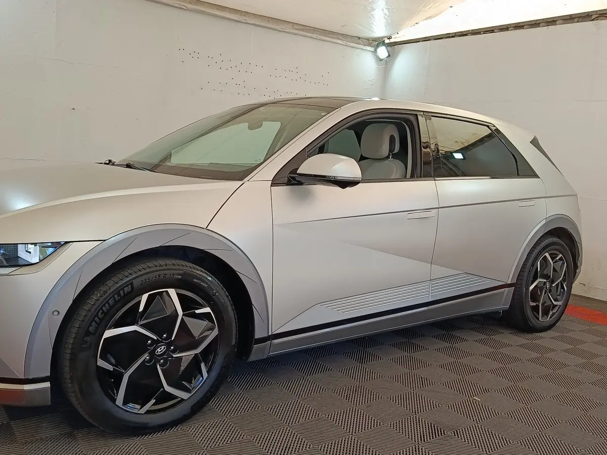 Vue latérale droite d'une Hyundai IONIQ électrique beige 2023 avec jantes noires et détails anguleux sur la carrosserie.