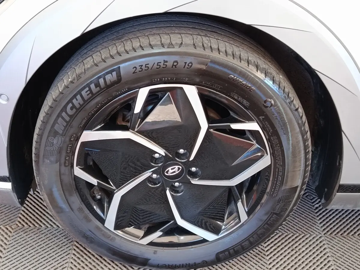 Gros plan sur la roue avant droite beige d’une Hyundai IONIQ BEV 77KWH AWD Executive avec jante noire et argentée.