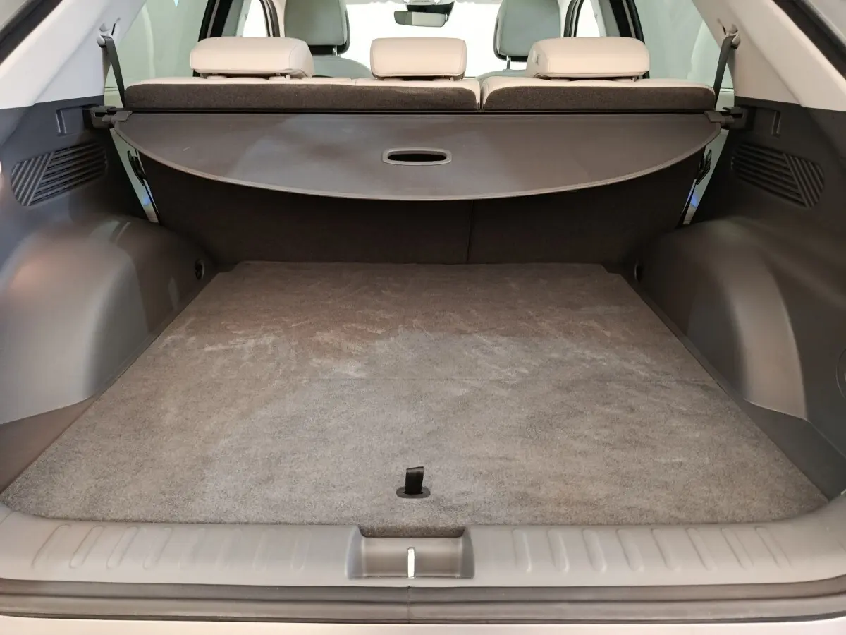 Coffre ouvert vu de l'arrière d'une Hyundai IONIQ beige 2023, avec banquette arrière et cache-bagages déployé.