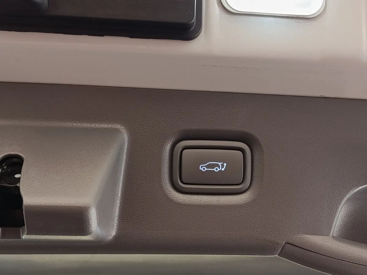 Bouton d'ouverture électrique du coffre sur la garniture intérieure beige d'une Hyundai IONIQ BEV 77KWH AWD Executive 2023.