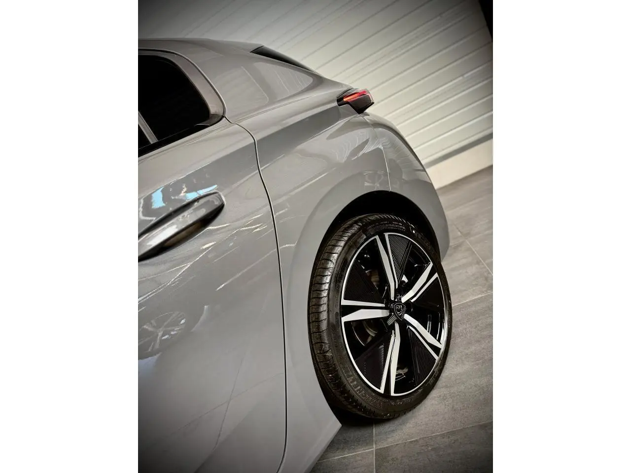 Gros plan sur l’aile arrière droite gris selenium d’une Peugeot 308 GT avec jante alliage noire et argentée.