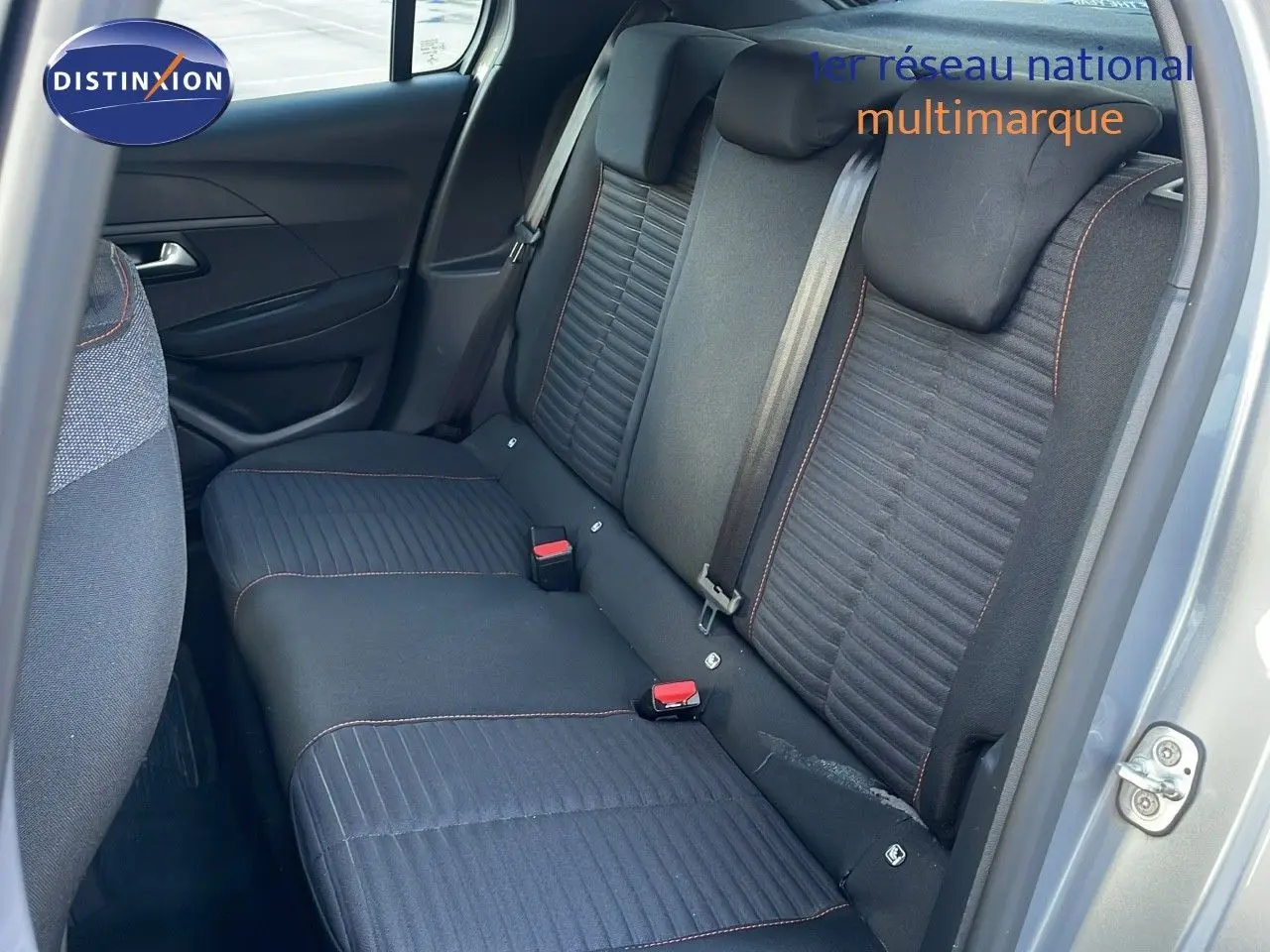 Vue intérieure sur la banquette arrière en tissu gris noir avec surpiqûres orange d'une Peugeot 208 électrique gris Artense.