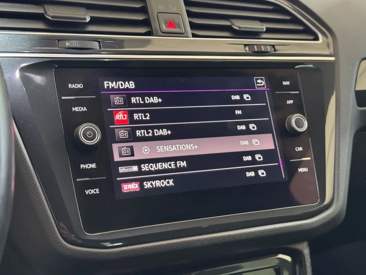 Écran tactile central du tableau de bord du Volkswagen Tiguan 2021 affichant les stations radio FM/DAB.