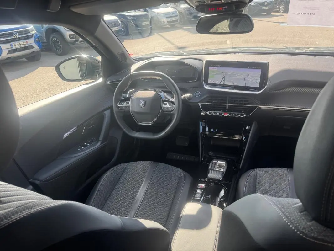 Vue intérieure avant du Peugeot 2008 Hybrid gris, montrant le volant compact, l'écran tactile et les sièges en tissu noir.