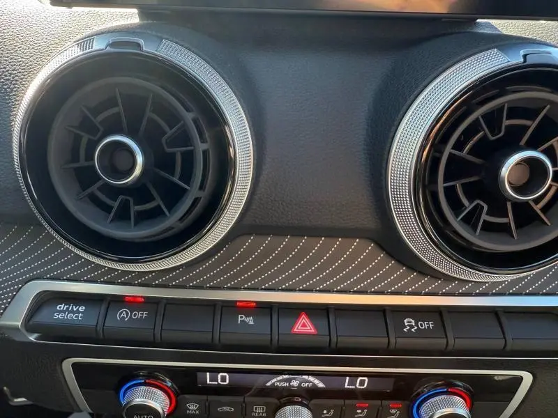 Vue rapprochée des aérateurs ronds et de la console centrale avec boutons de contrôle sur l'Audi Q2 Gris Daytona nacré 2025.