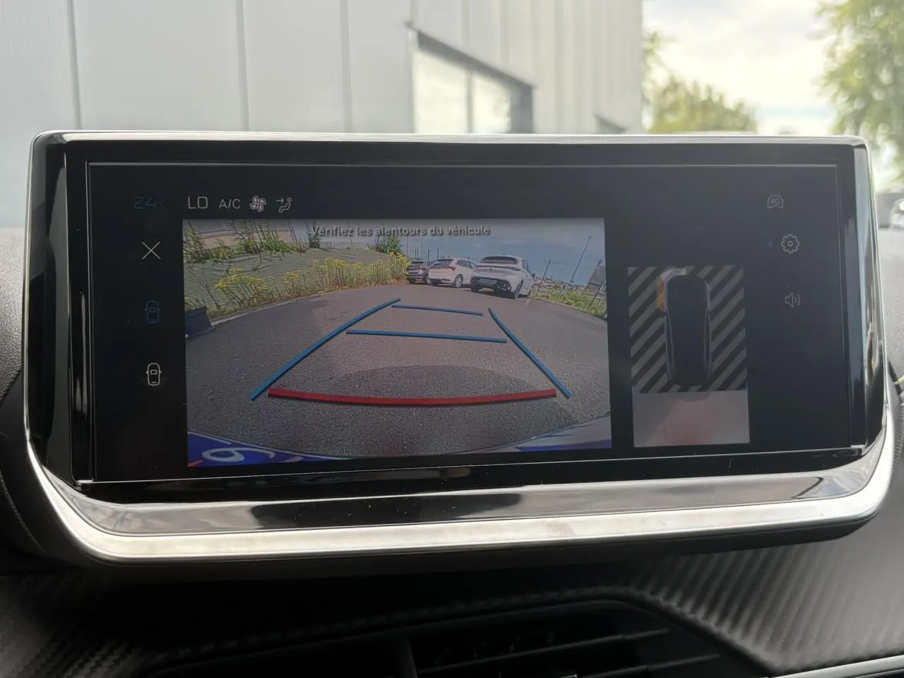 Écran tactile intérieur montrant la caméra de recul d’une Peugeot 208 Hybrid 110 e-DSC6 GT en stationnement.