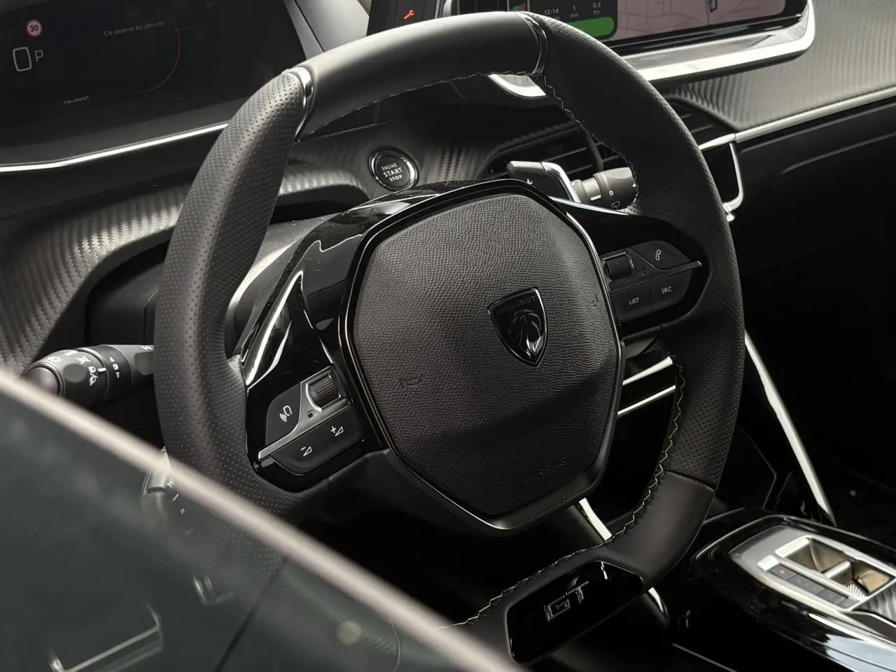 Vue rapprochée du volant compact cuir noir avec badge GT et commandes intégrées du Peugeot 208 Hybrid 110 e-DSC6.