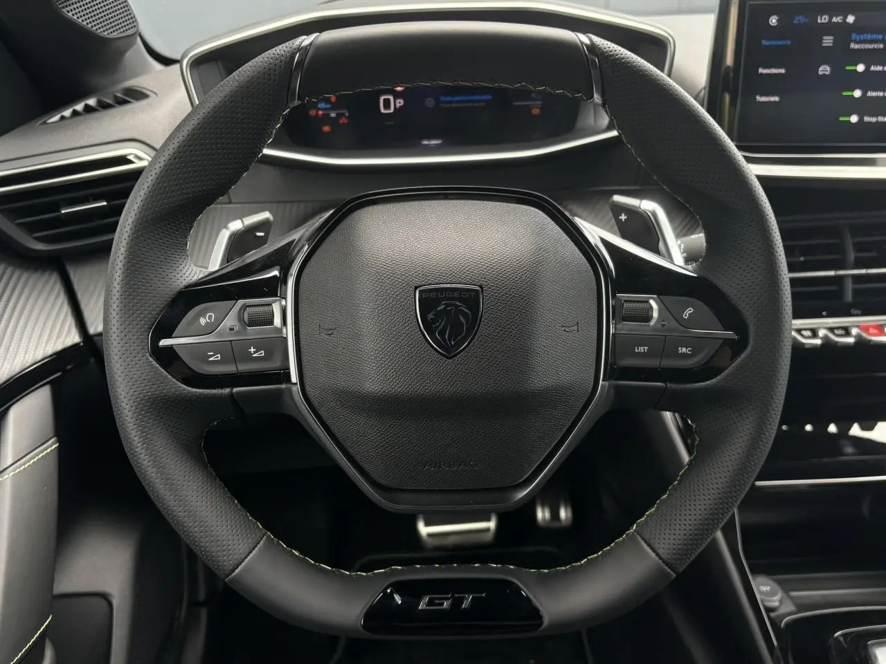 Volant compact cuir noir avec badge GT et commandes intégrées, vue frontale du poste de conduite Peugeot 208 Hybrid 2025.