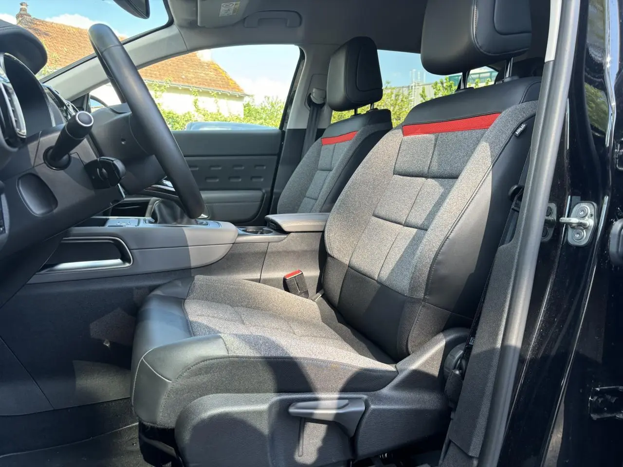 Vue intérieure côté conducteur du Citroën C5 Aircross noir métallisé, mettant en valeur les sièges Advanced Comfort gris avec bande rouge.