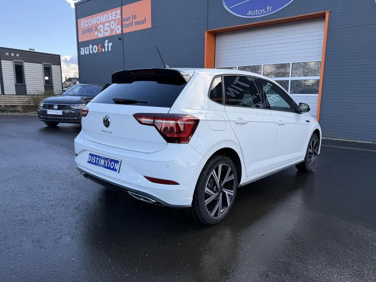 Volkswagen Polo blanc pur en 3/4 arrière droit, vitres surteintées et jantes alliage 17 pouces R-Line visibles.