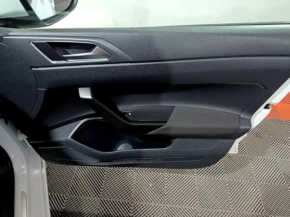 Vue rapprochée de la porte avant gauche blanche du Volkswagen Taigo 2022 avec poignée intérieure noire et garniture texturée.