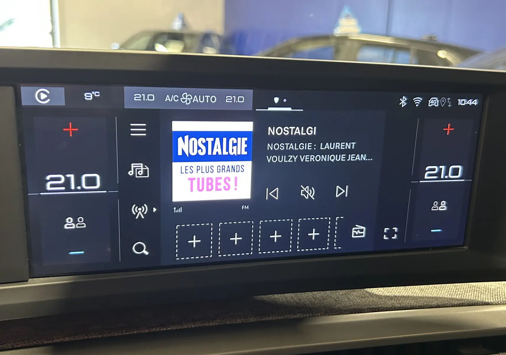 Écran tactile central du tableau de bord de la Peugeot 5008 III Hybrid, affichant la radio et la climatisation à 21°C.