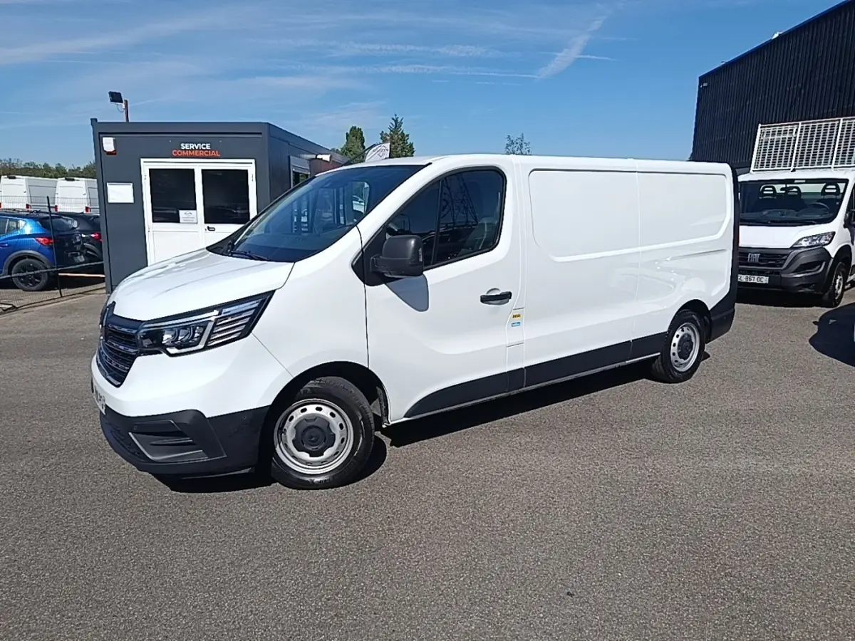 Renault Trafic Fourgon blanc en 3/4 avant droit, avec jantes acier et pare-chocs noirs, stationné en extérieur.