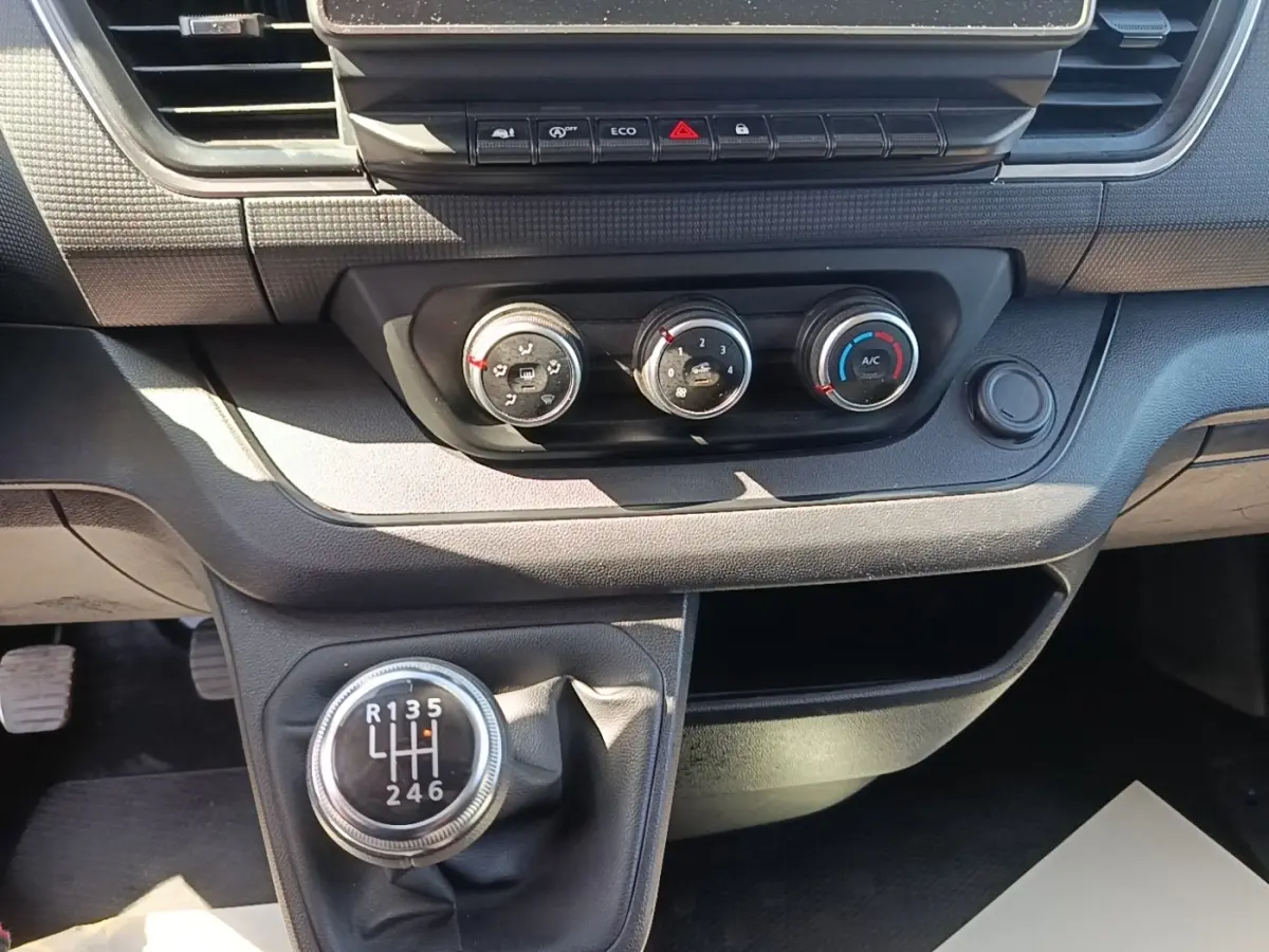 Vue rapprochée de la console centrale du Renault Trafic Fourgon 2023, avec levier de vitesses manuel et commandes de climatisation.