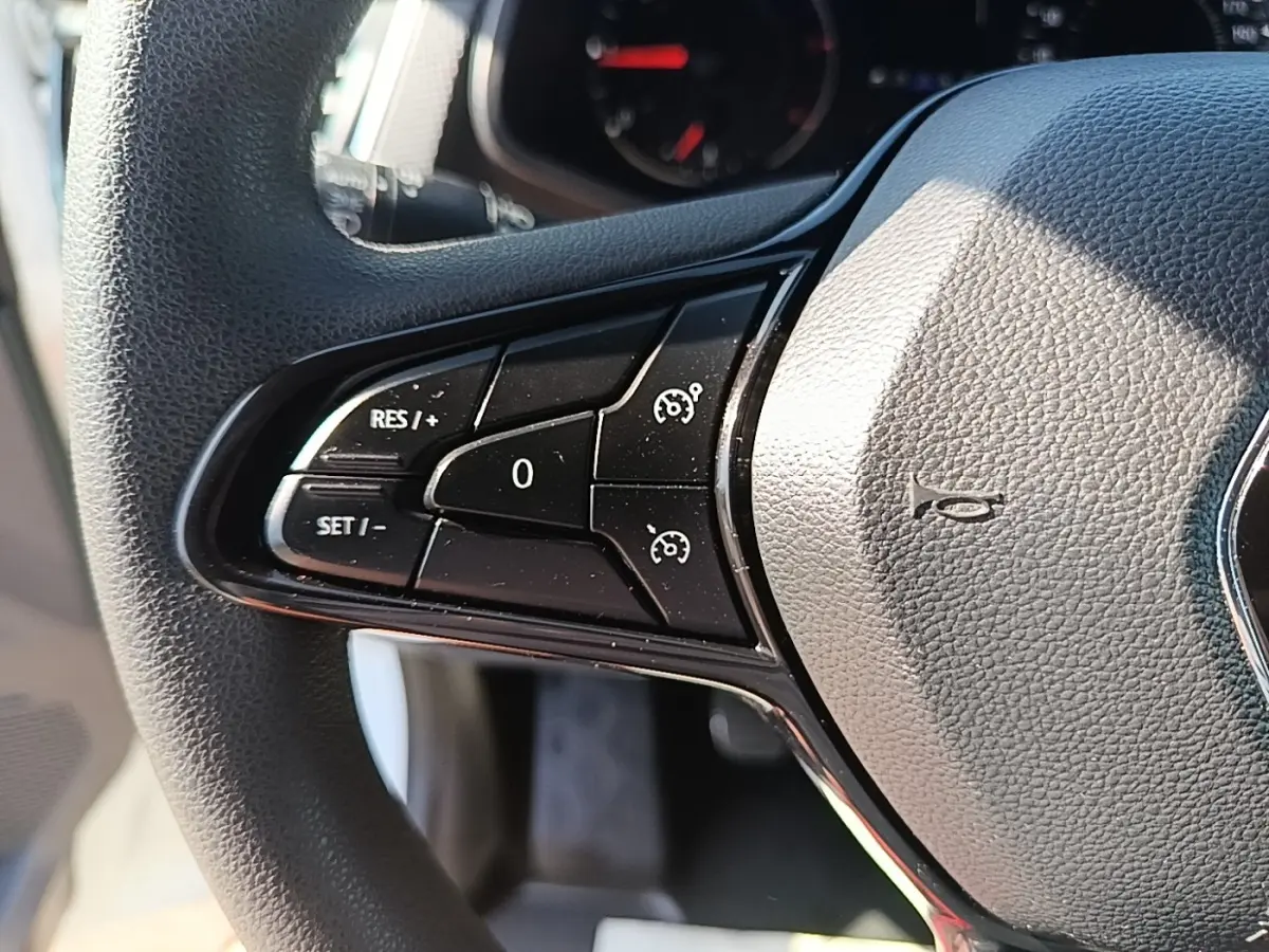 Gros plan sur le volant multifonctions noir du Renault Trafic Fourgon blanc, montrant les commandes de régulateur de vitesse.