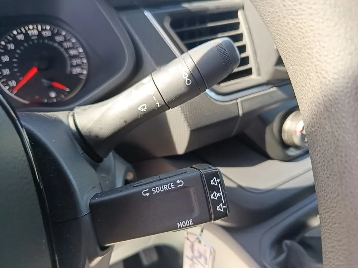 Détail du commodo gauche noir avec commandes audio sur le volant d'un Renault Trafic Fourgon blanc, intérieur gris.