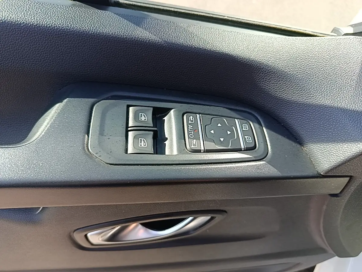 Gros plan sur les commandes de lève-vitres et rétroviseurs électriques sur la porte côté conducteur du Renault Trafic blanc.