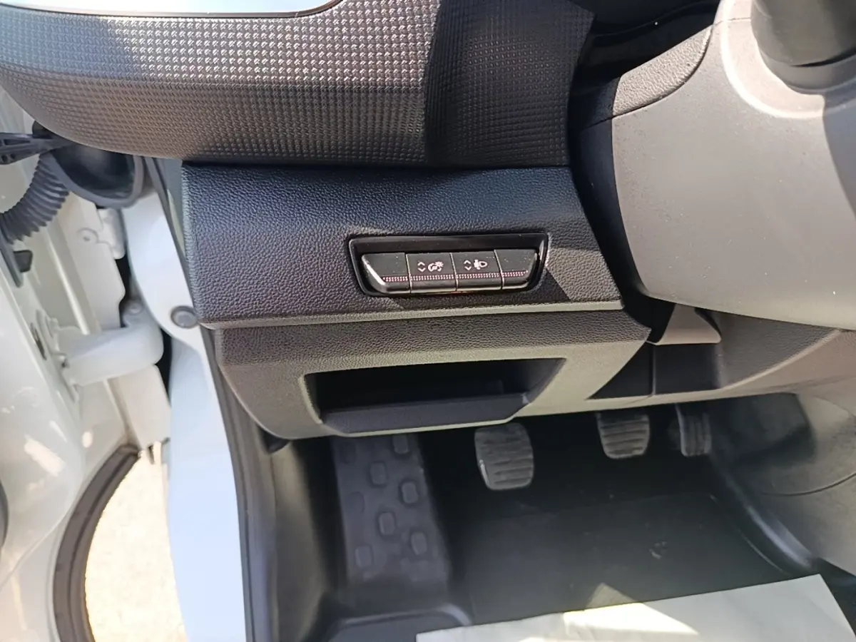 Vue intérieure côté conducteur du Renault Trafic Fourgon blanc 2023, avec pédales et commandes sous le tableau de bord.