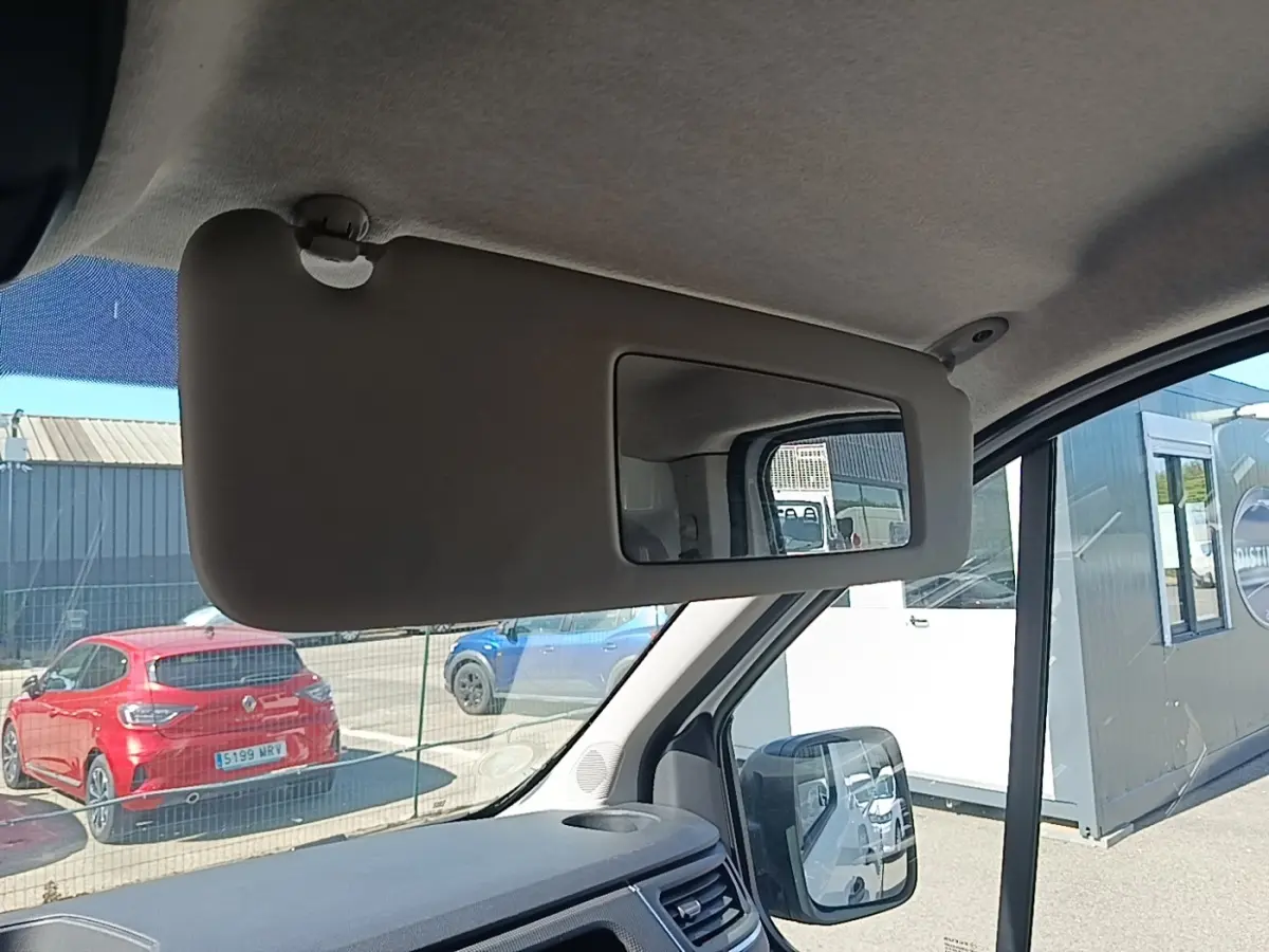 Vue intérieure du pare-soleil côté conducteur du Renault Trafic Fourgon blanc, avec rétroviseur et tableau de bord partiellement visibles.