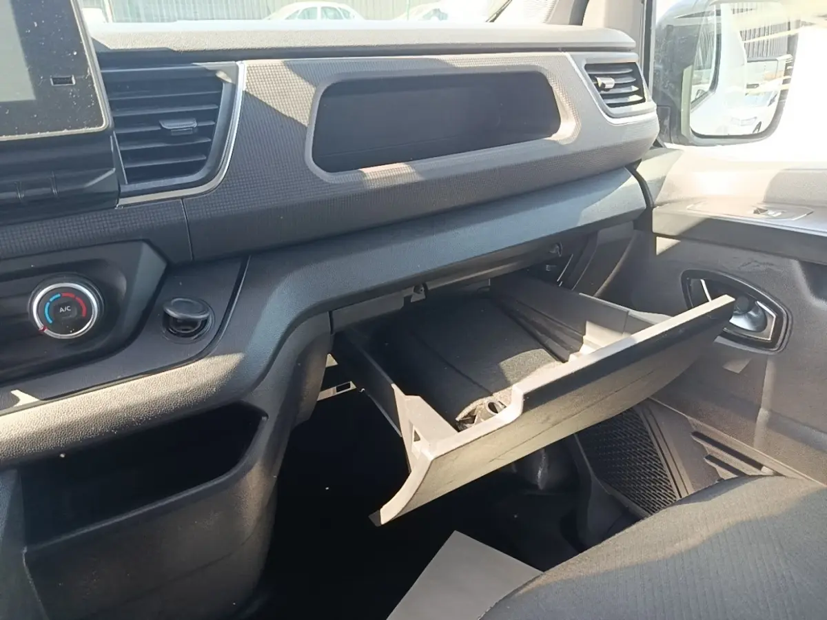 Vue intérieure côté passager du Renault Trafic Fourgon 2023, boîte à gants ouverte et tableau de bord noir.