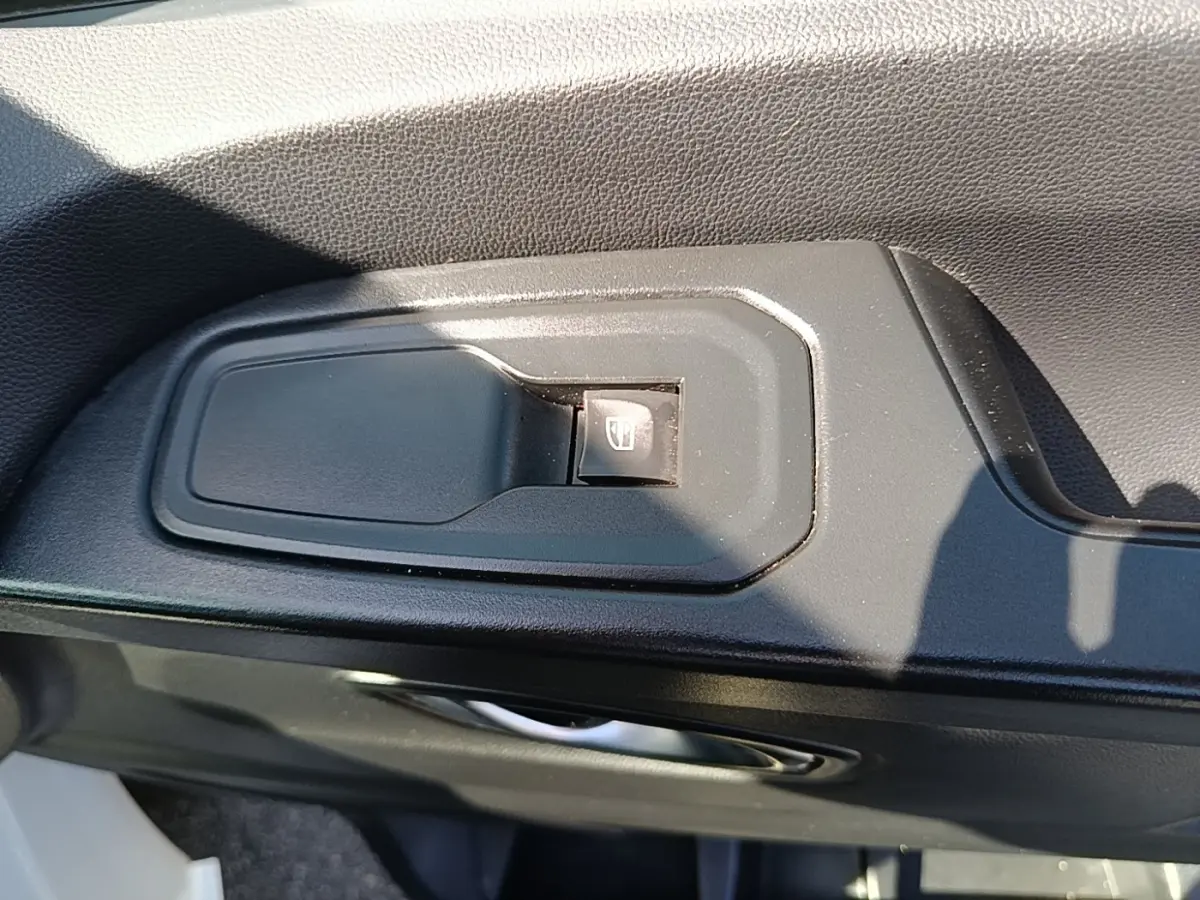 Gros plan sur le bouton de commande de lève-vitre côté conducteur dans l’habitacle du Renault Trafic Fourgon blanc 2023.