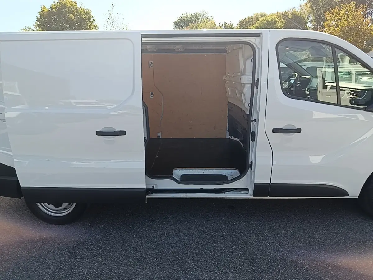 Vue latérale droite d’un Renault Trafic Fourgon blanc 2023 avec porte coulissante ouverte montrant l’espace de chargement vide.