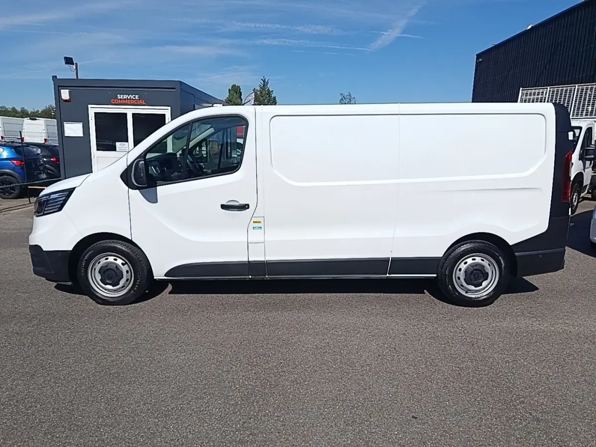 Renault Trafic Fourgon blanc vu de profil côté gauche, avec jantes acier et carrosserie lisse sans fenêtres.