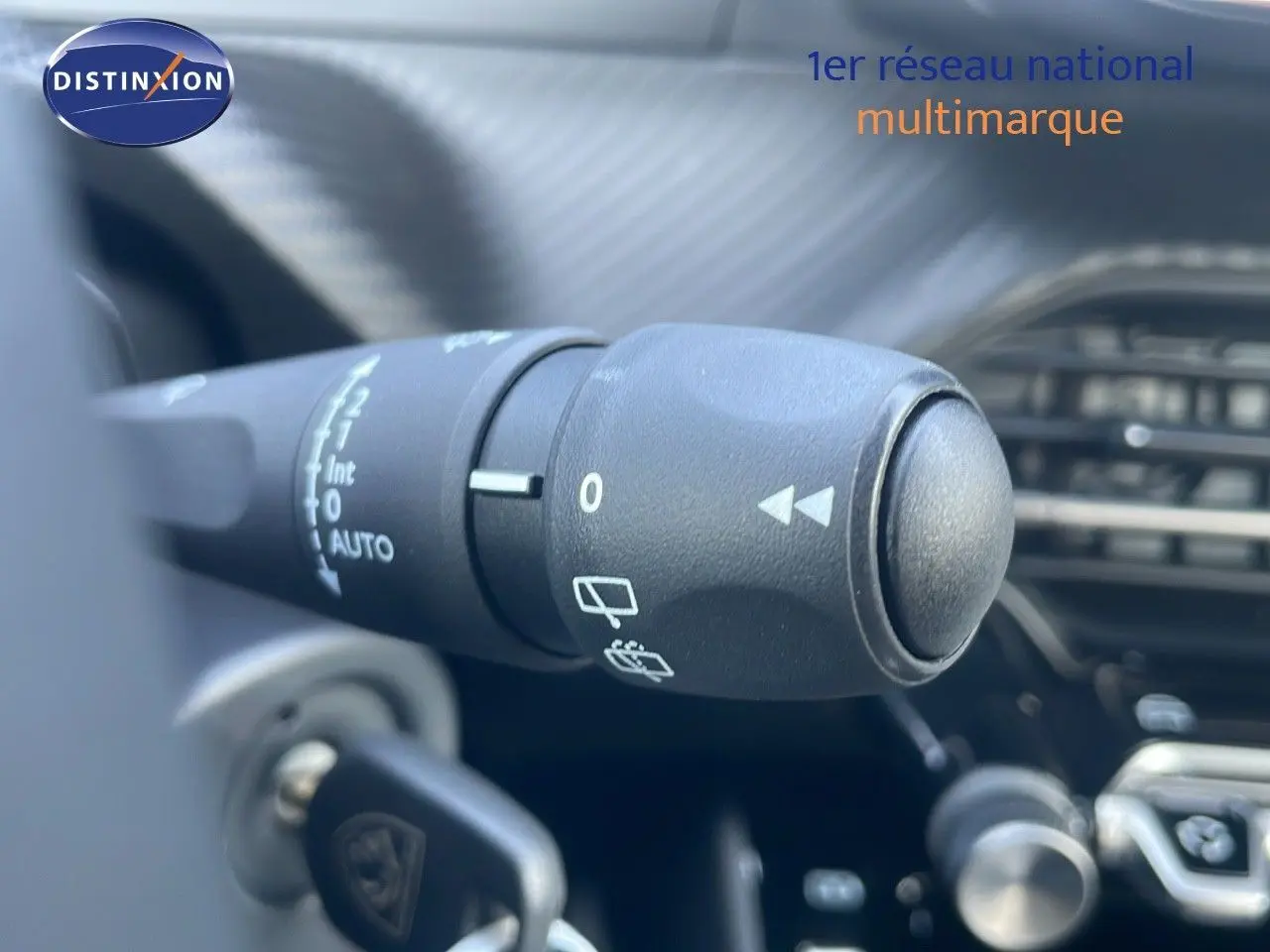 Gros plan sur la commande d'essuie-glace du Peugeot 2008 Hybrid gris, montrant les réglages et le tableau de bord flou en arrière-plan.