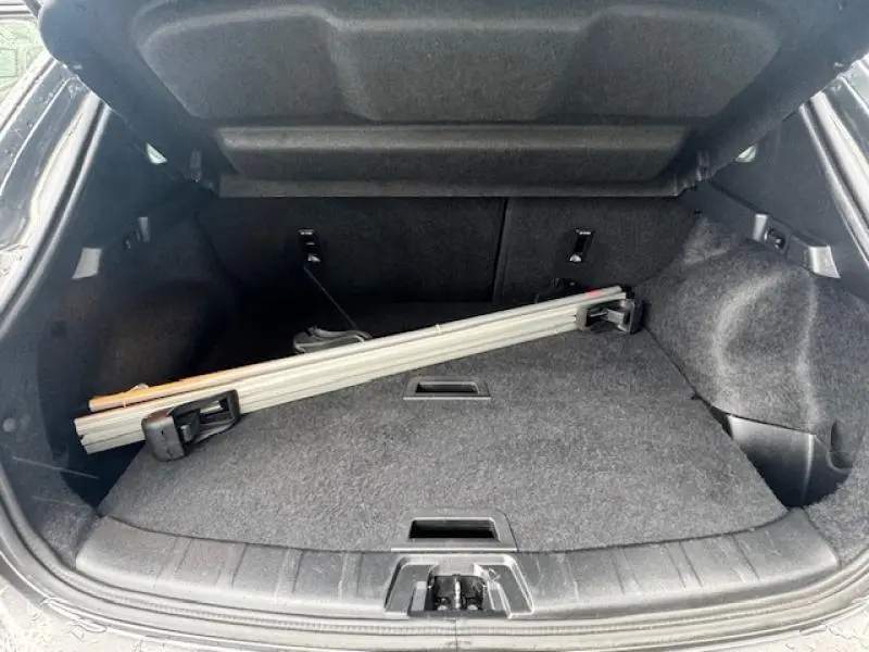 Coffre ouvert du Nissan Qashqai gris Squale 2015, vue intérieure montrant un chargement léger sur la moquette.