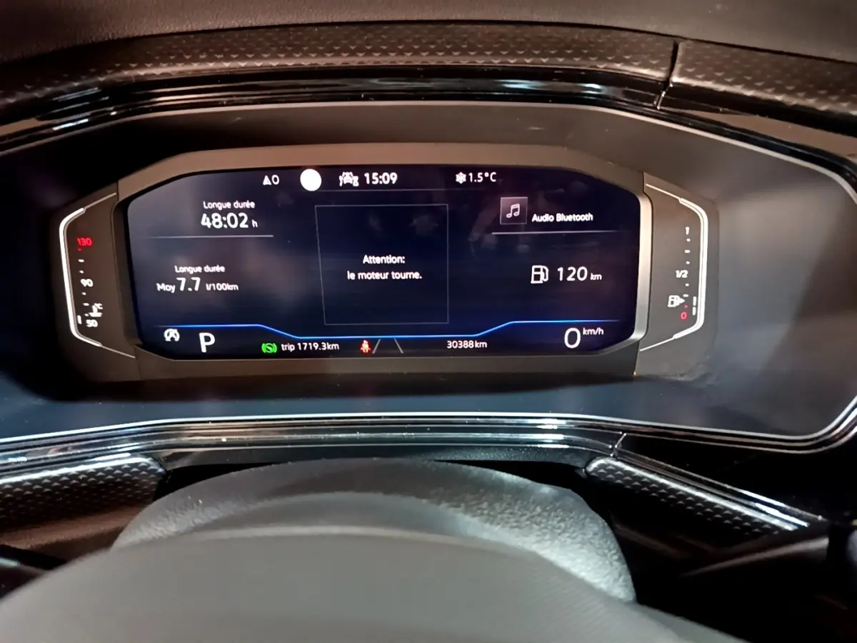 Vue rapprochée du combiné d'instruments numérique du Volkswagen T-Cross 2023 affichant vitesse, autonomie et alertes moteur.