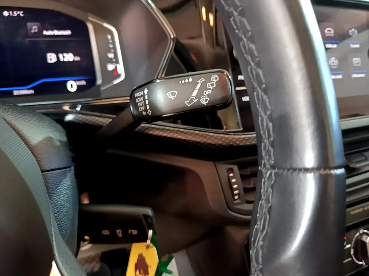 Gros plan sur le volant cuir et la commande d’essuie-glace du tableau de bord du Volkswagen T-Cross gris foncé 2023.