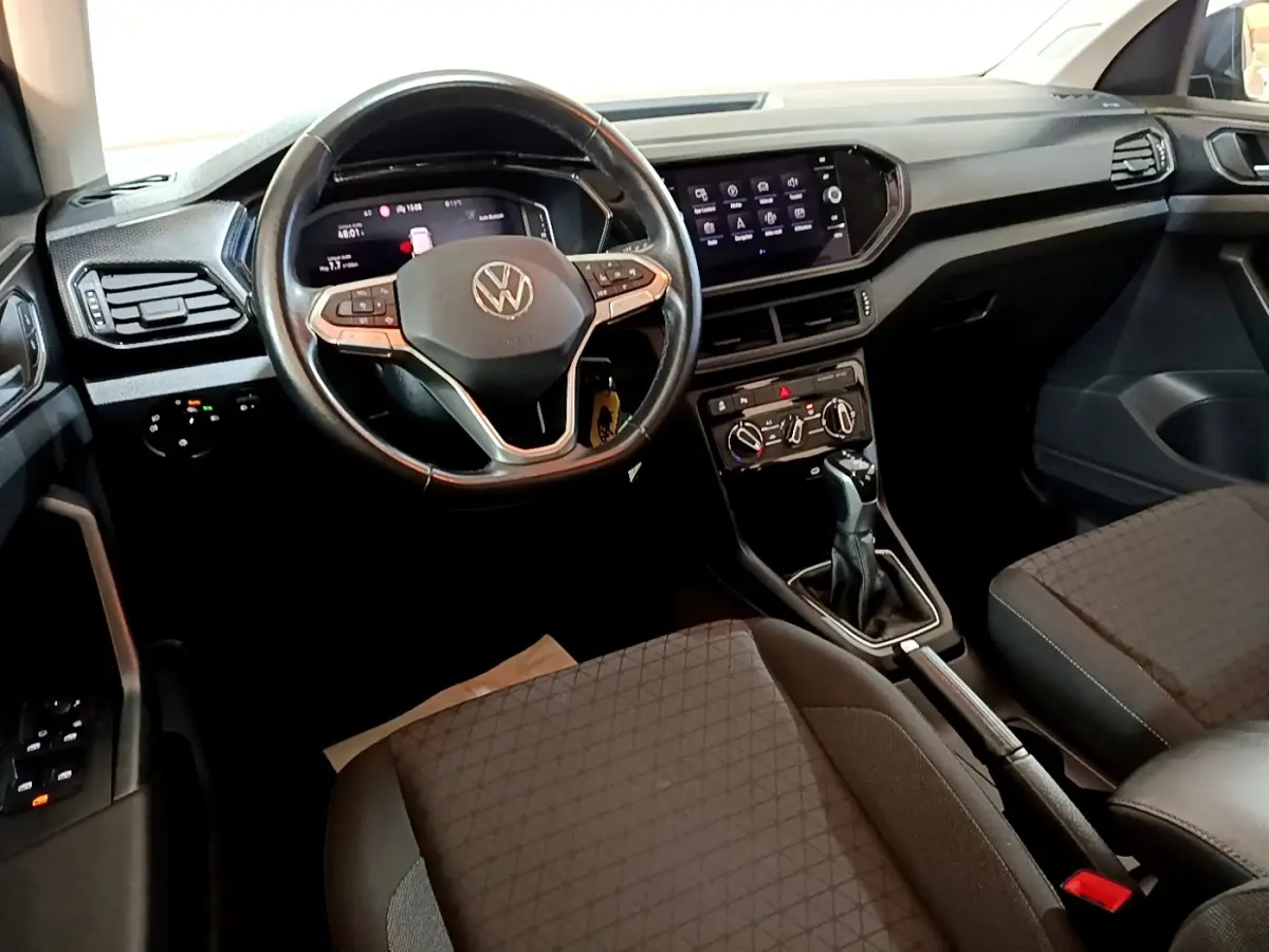 Vue intérieure du tableau de bord et volant cuir multifonctions du Volkswagen T-Cross 2023, ambiance noire et moderne.